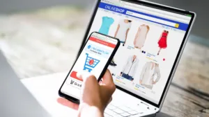 Person using a smartphone and laptop to browse an e-commerce website, illustrating the importance of mobile-first website development for modern online businesses.